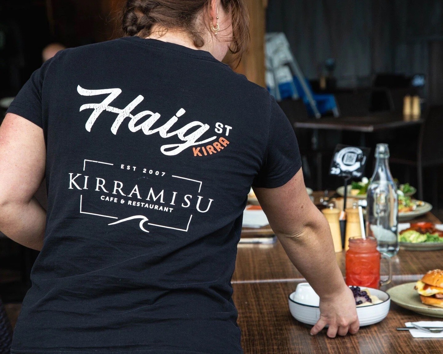 Haig St team member setting a table, wearing the family's Haig St and Kirramisu uniform