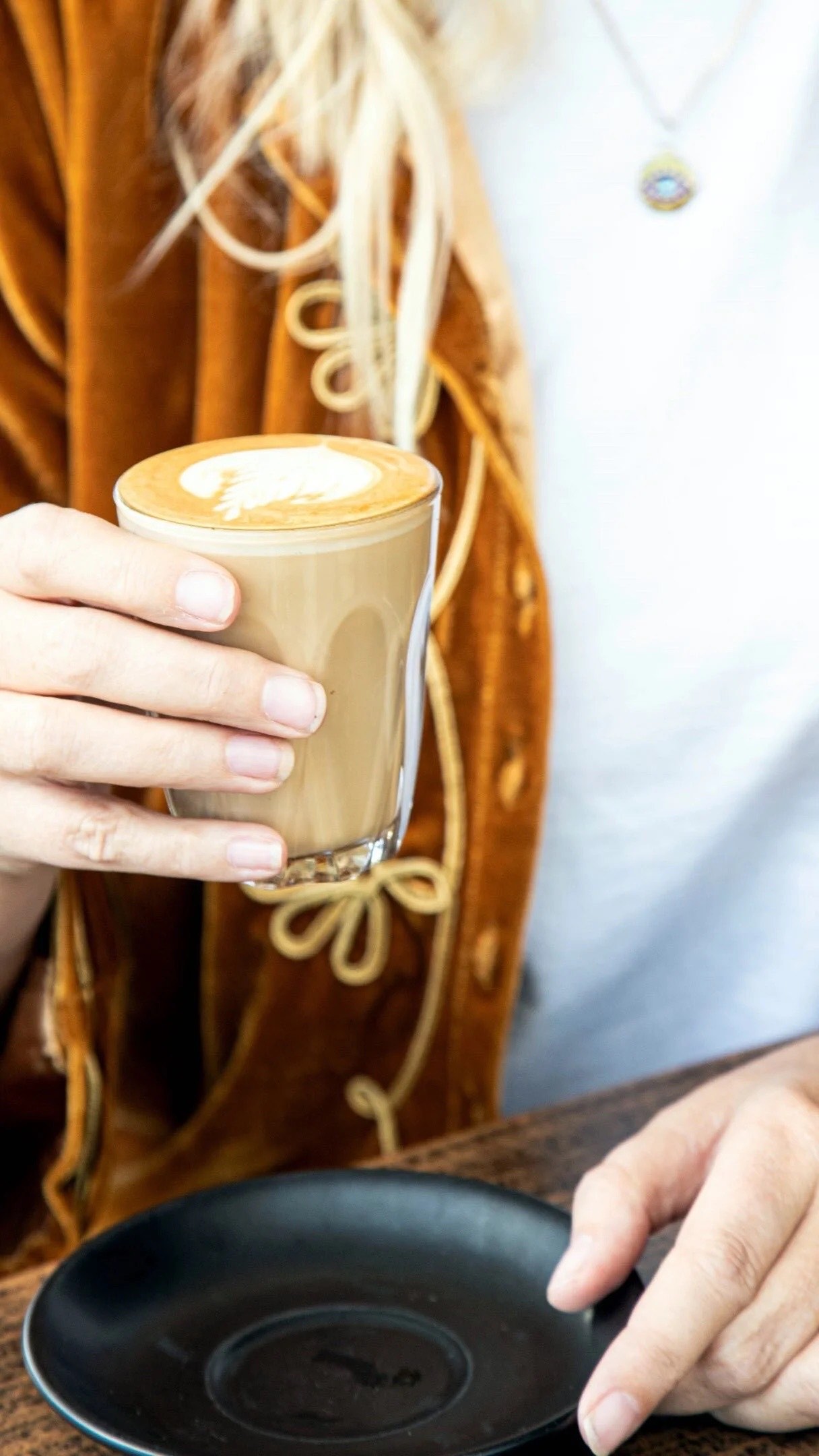 Takeaway flat white made at Haig St Cafe, held up in the sun outside on the Kirra beachfront